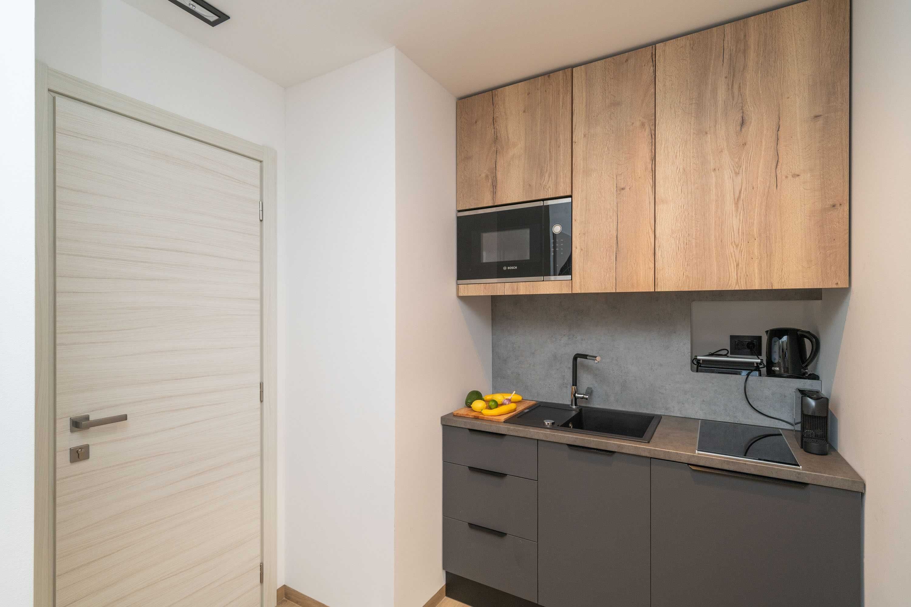 A compact kitchen with a microwave, sink, and a coffee maker.