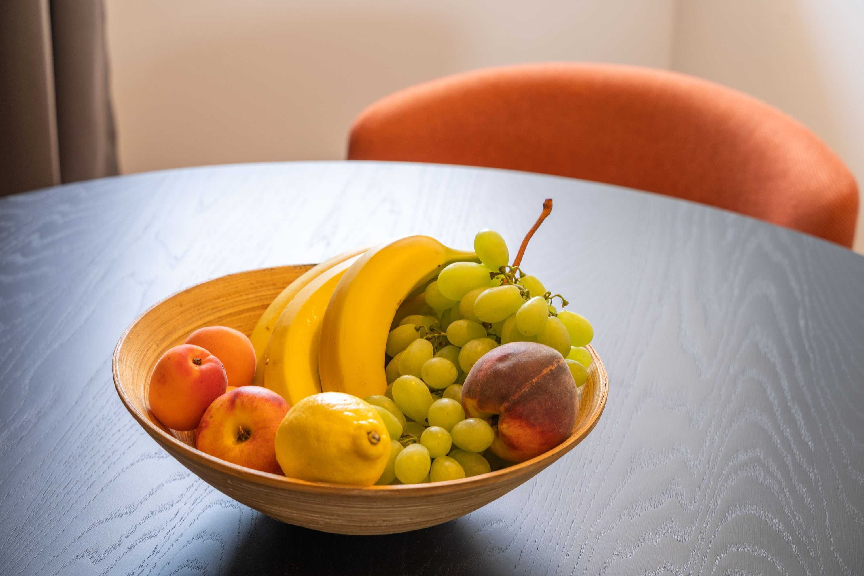 Un saladier en bois rempli de fruits, posé sur une table.