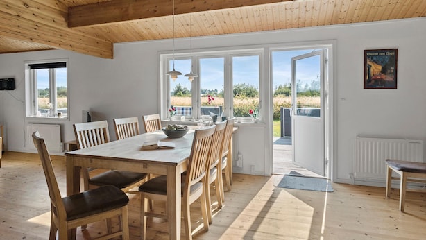 Un'ampia sala da pranzo con tavolo e sedie in legno, ampie finestre e vista sull'esterno.