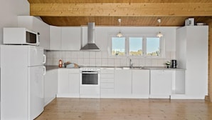 Una cucina moderna con mobili bianchi, forno integrato, microonde e una finestra vista all'esterno.