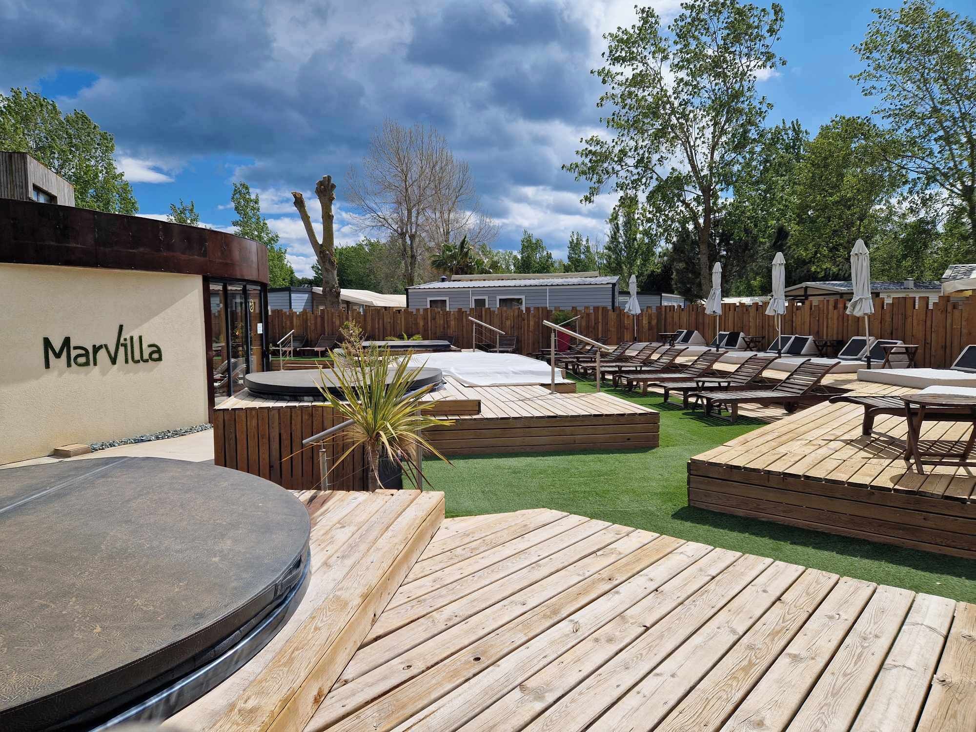 A Marvilla outdoor area with wooden deck, lounge chairs, and a pool.
