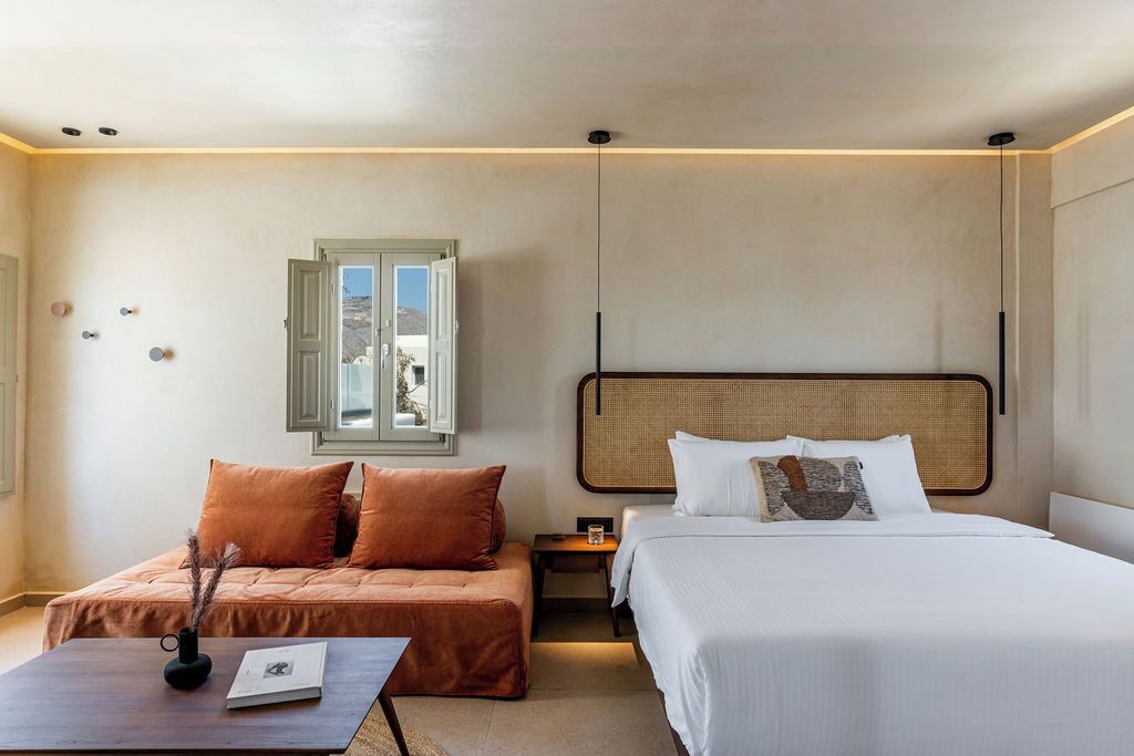 Une chambre d’hôtel avec un lit, un canapé, une table de chevet et une fenêtre.