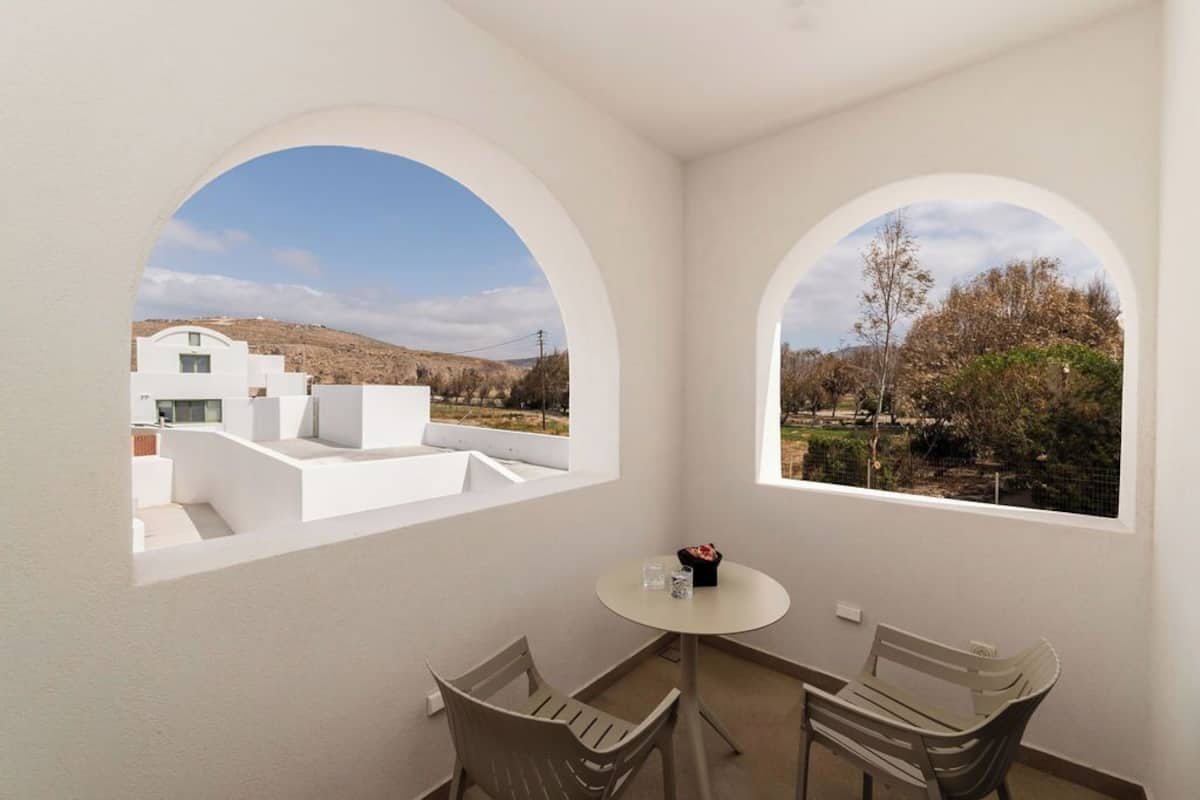 A room with two arched windows, a small round table, and two chairs.