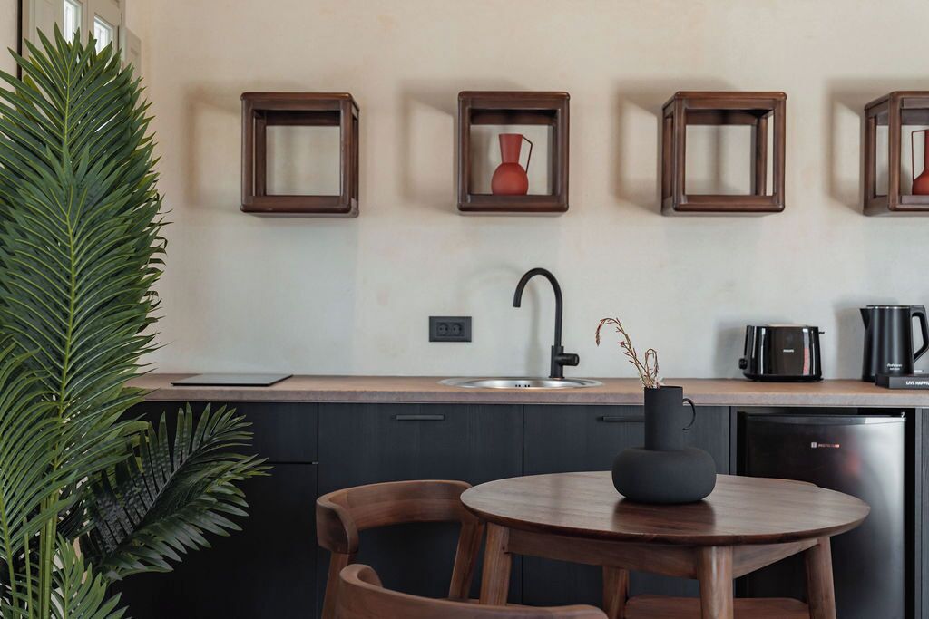 Una cucina moderna con mobili scuri, un tavolo rotondo in legno e una pianta in vaso.