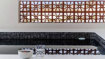 Enjoy a tranquil space with a small table, bowl of fresh fruit, and a decorative metal partition.
