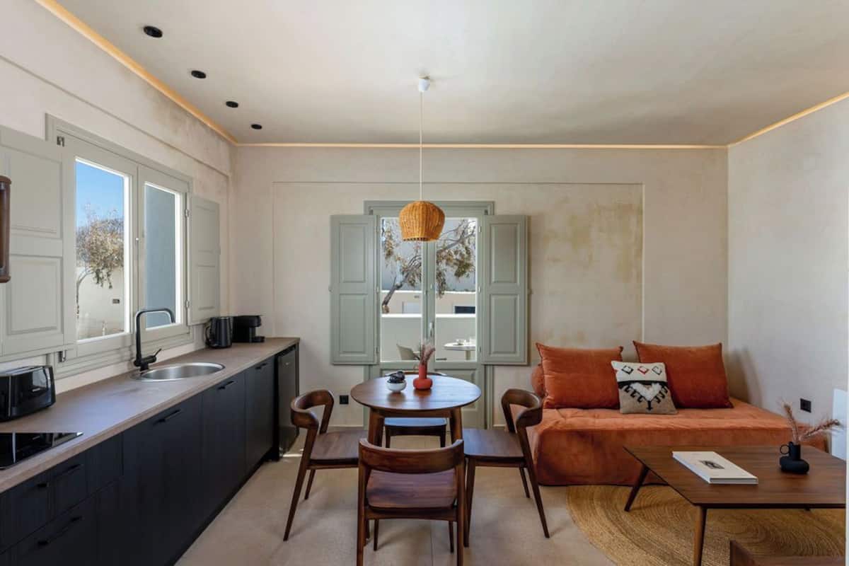 A modern kitchen with a dining area, a sofa, and a table with a vase.