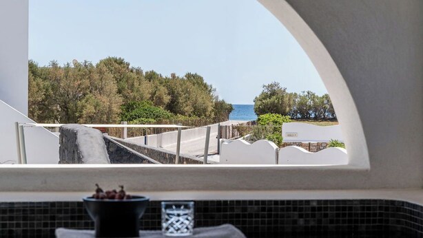 A view from a window with a tiled floor, a small bowl of grapes, and a decorative item. - Peranosa The Residency (Santorini)