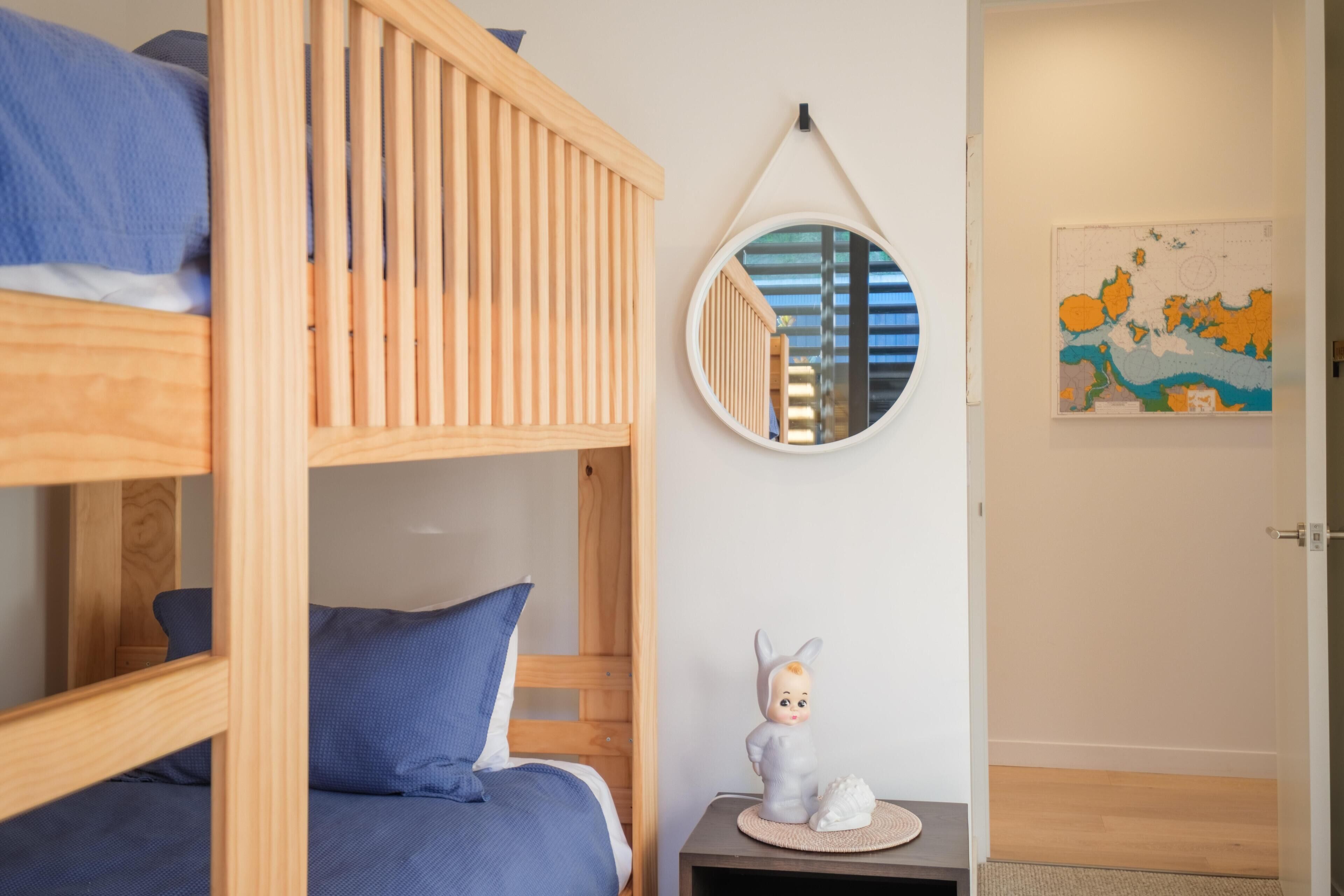 A bunk bed room with a round mirror, a small table with a figurine, and a map on the wall.