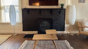 A living room with a fireplace, a ceiling fan, a sofa, and a coffee table. - Mid-Century Modern retreat (Visalia)