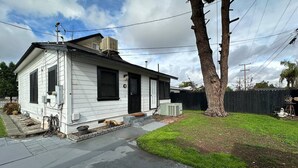 A single-story mobile home with a front porch, a small front yard, and a tree to the right. - Mid-Century Modern retreat (Visalia)