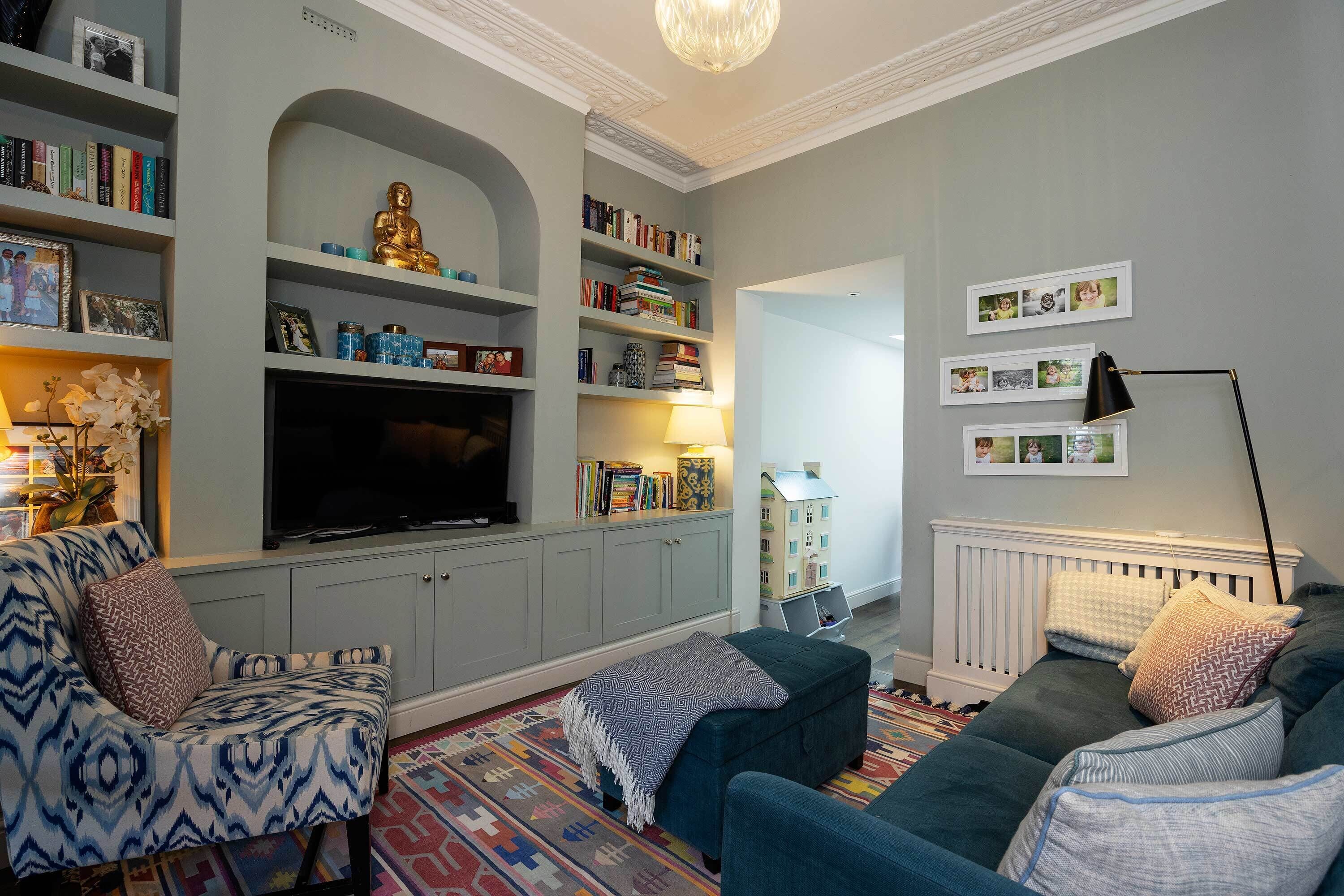 Ein Wohnzimmer mit einer Couch, Sesseln, einem Fernseher, Bücherregalen und einer dekorativen Buddha-Statue.