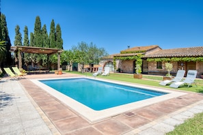 A rectangular swimming pool with a pergola and lounge chairs, surrounded by a stone building with vines. - MAS MILLET: Beautiful country house in Albons with private pool (Albons)