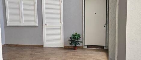A room with a wooden floor, two white sliding doors, a closed door, and a small potted plant.