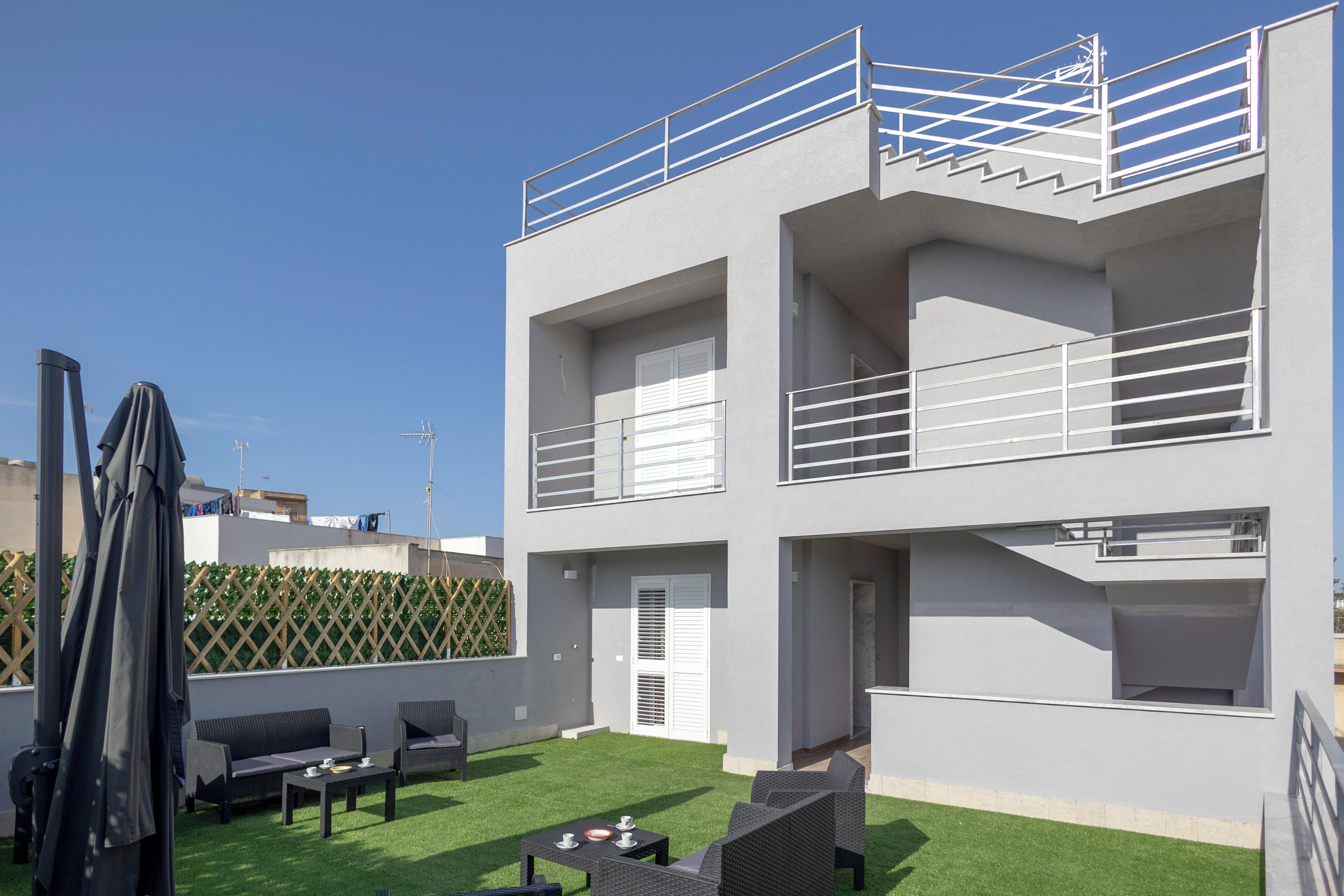 A modern two-story building with a rooftop patio, outdoor seating, and a staircase.