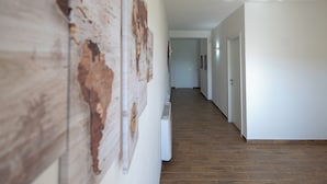 A hallway with a wooden floor, white walls, and a radiator. - ELYSIUM (Mazara del Vallo)