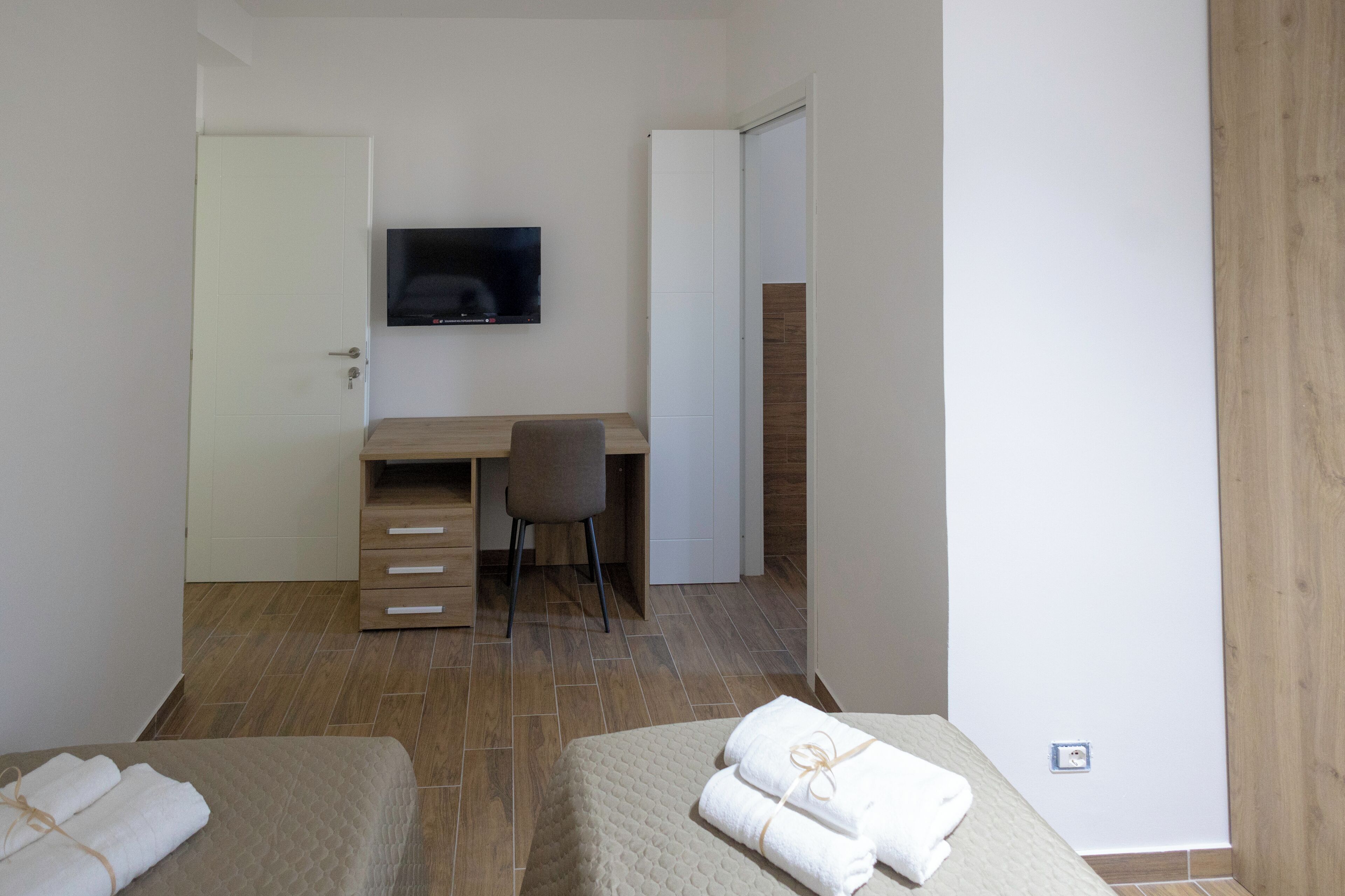 Een slaapkamer met twee bedden, een bureau en een televisie.