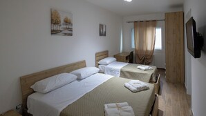 A hotel room with two beds, a desk, a TV, and artwork on the walls. - ELYSIUM (Mazara del Vallo)