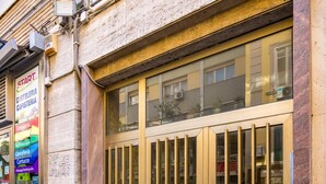 A building facade with a large, ornate metal gate, a sign for a car rental service, and a cobblestone street. - Chiave di Fuga - Doppia Deluxe (Naples)