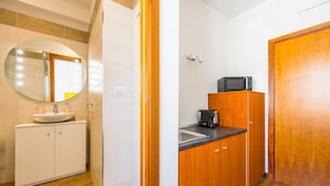 Cocina compacta con fregadero, microondas y armarios de madera.