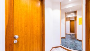A hallway with a wooden door, a tiled floor, and a mirrored wall. - Chiave di Fuga - Doppia Classic (Naples)