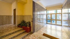 A lobby with a tiled floor, a marble wall, and a door leading outside. - Chiave di Fuga - Doppia Classic (Naples)