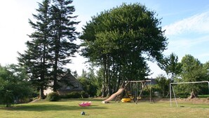 Ein Rasenplatz mit Schaukel, Rutsche und Fußballtor.