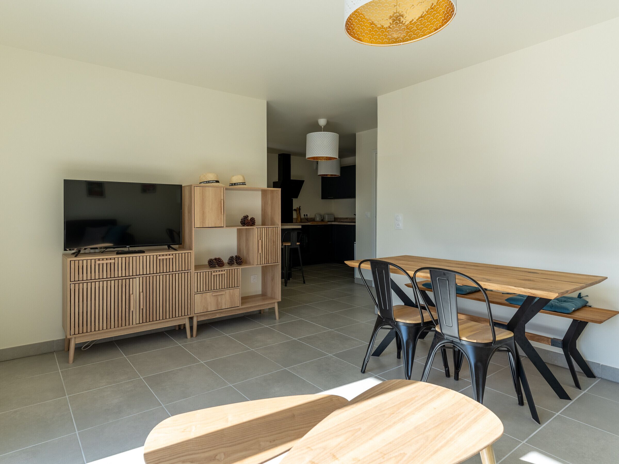 Un soggiorno moderno con un mobile TV in legno, una TV a schermo piatto e un'area pranzo con tavolo e sedie in legno.