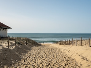 Ein Sandstrand mit einer Holzlattenverkleidung und einem Gebäude mit rotem Dach.