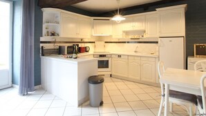 A modern kitchen with white cabinets, a central island, and a built-in oven. - Charming house in Vessey with TV and internet (Pontorson)