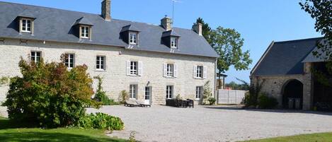 A large stone building with multiple windows and a gravel driveway.