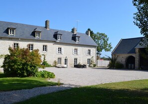 A large stone building with multiple windows and a gravel driveway.