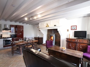 A spacious kitchen with modern appliances, a dining area with a wooden table, and a fireplace.