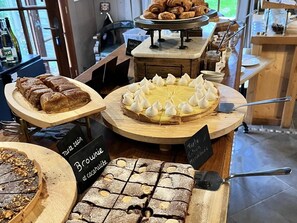 A variety of desserts displayed on wooden stands in a café setting.