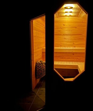 A wooden sauna with a hexagonal shape and a bench inside.