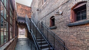 Ein schmaler Backstein-Gasse mit einer Metalltreppe, die zu einer zweiten Etage führt.