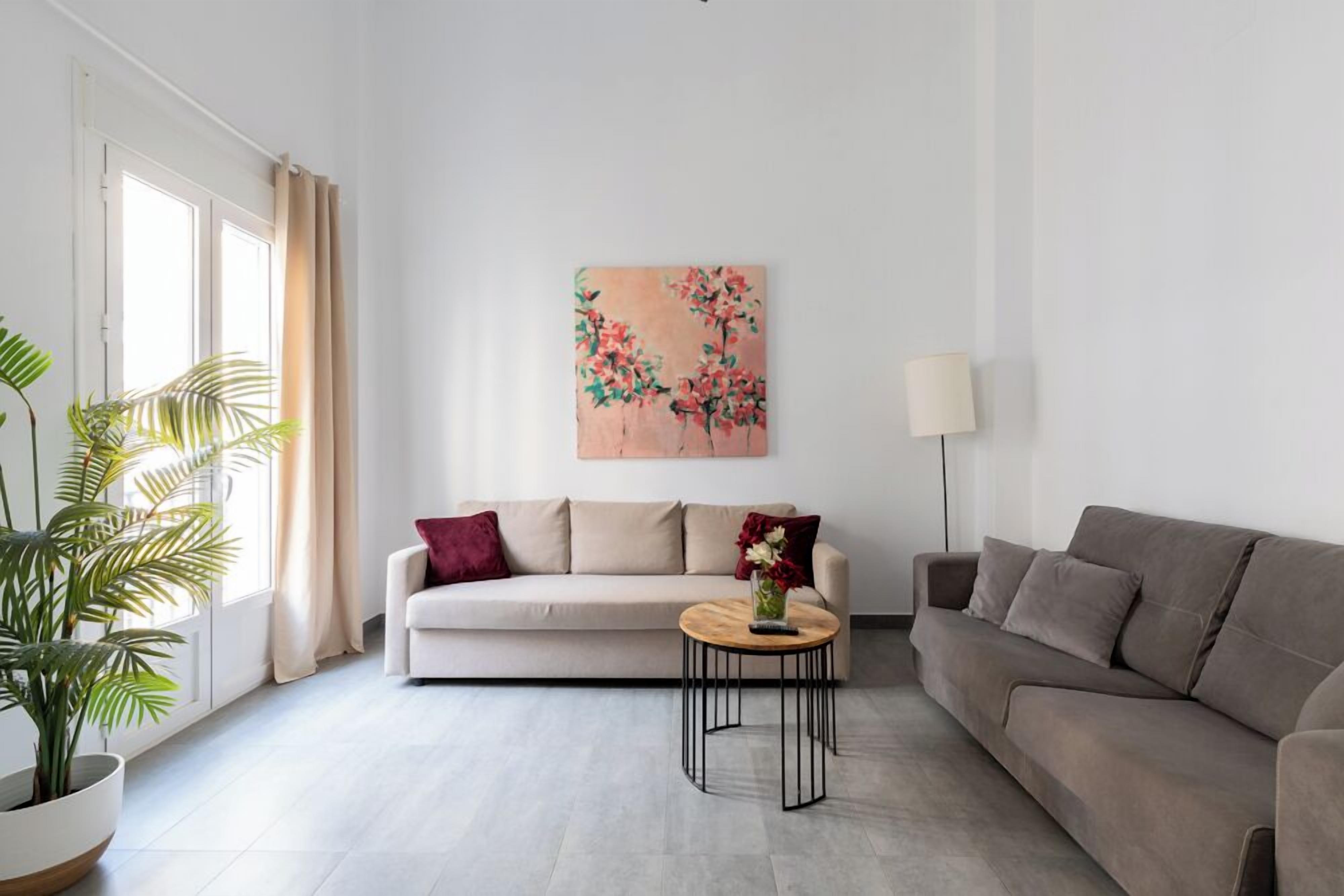 Un soggiorno moderno con un divano color beige, un tavolino in legno e un quadro con fiori sulla parete.