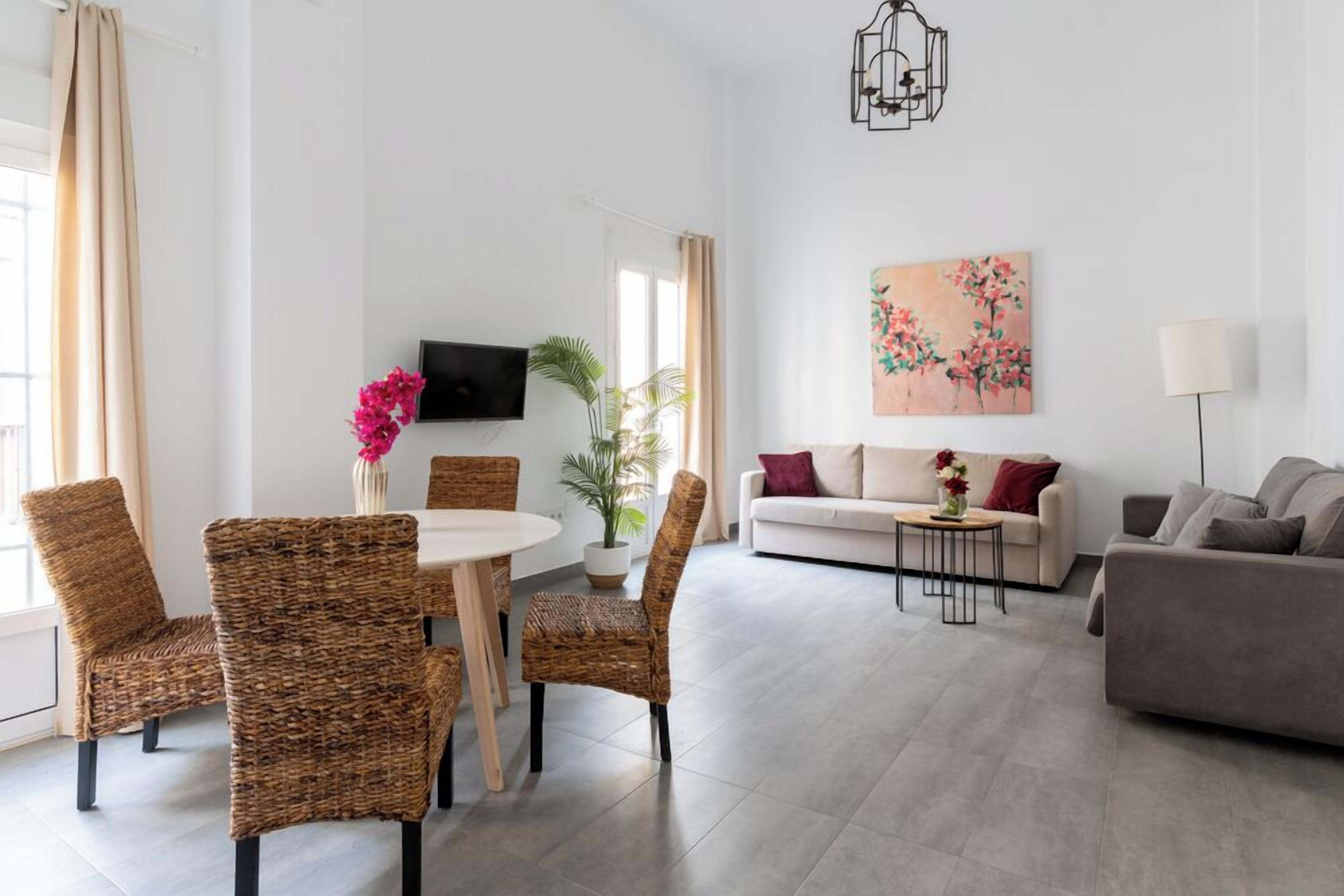 Una sala de estar moderna con comedor, un sofá, un televisor montado en la pared y un cuadro.