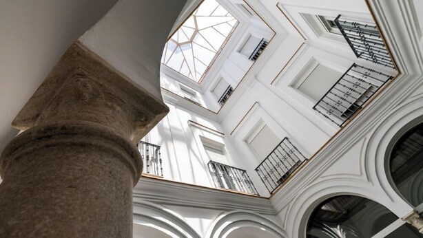 Un atrium à plusieurs niveaux, doté de murs blancs, de grandes fenêtres et d’une colonne centrale.