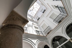Un atrio de varios niveles con paredes blancas, ventanas amplias y una columna central.