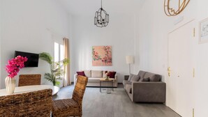 Un salon moderne avec un canapé, une table à manger et des chaises, un téléviseur et un tableau accroché au mur.