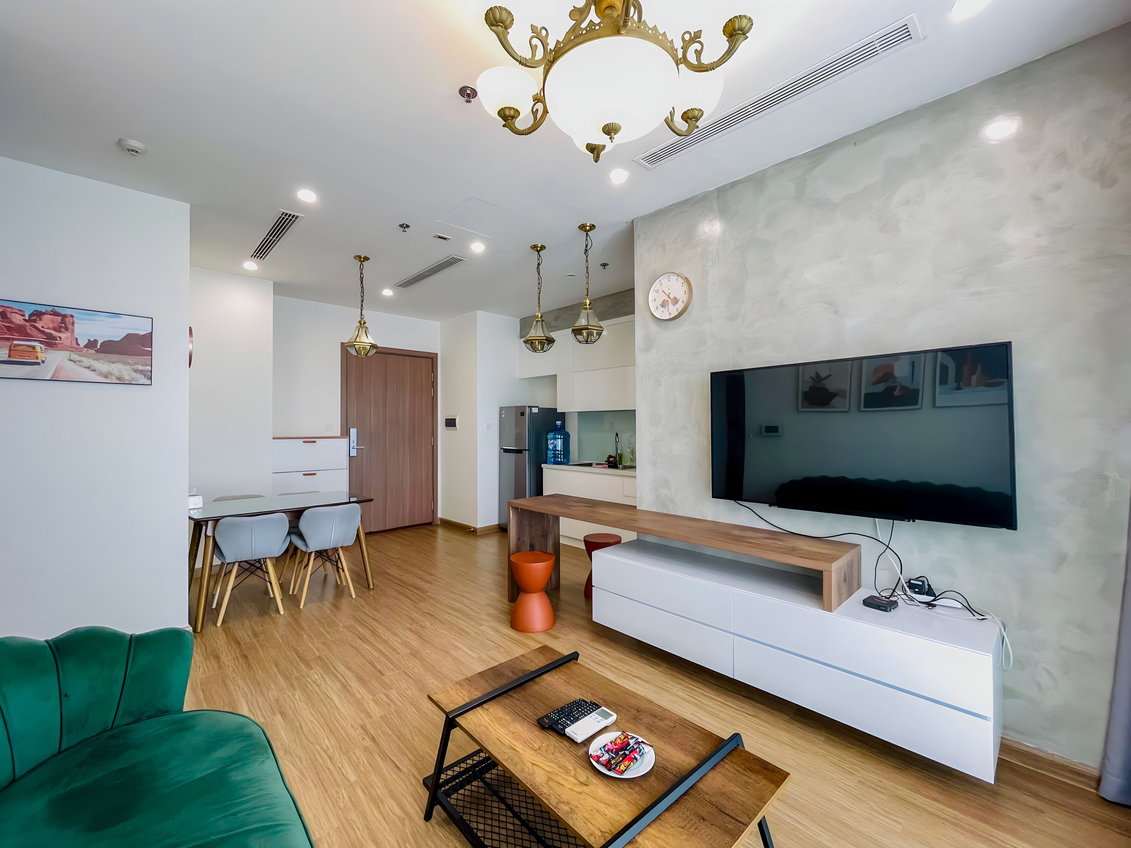 Un salon moderne avec un téléviseur à écran plat, des meubles en bois et un canapé vert.