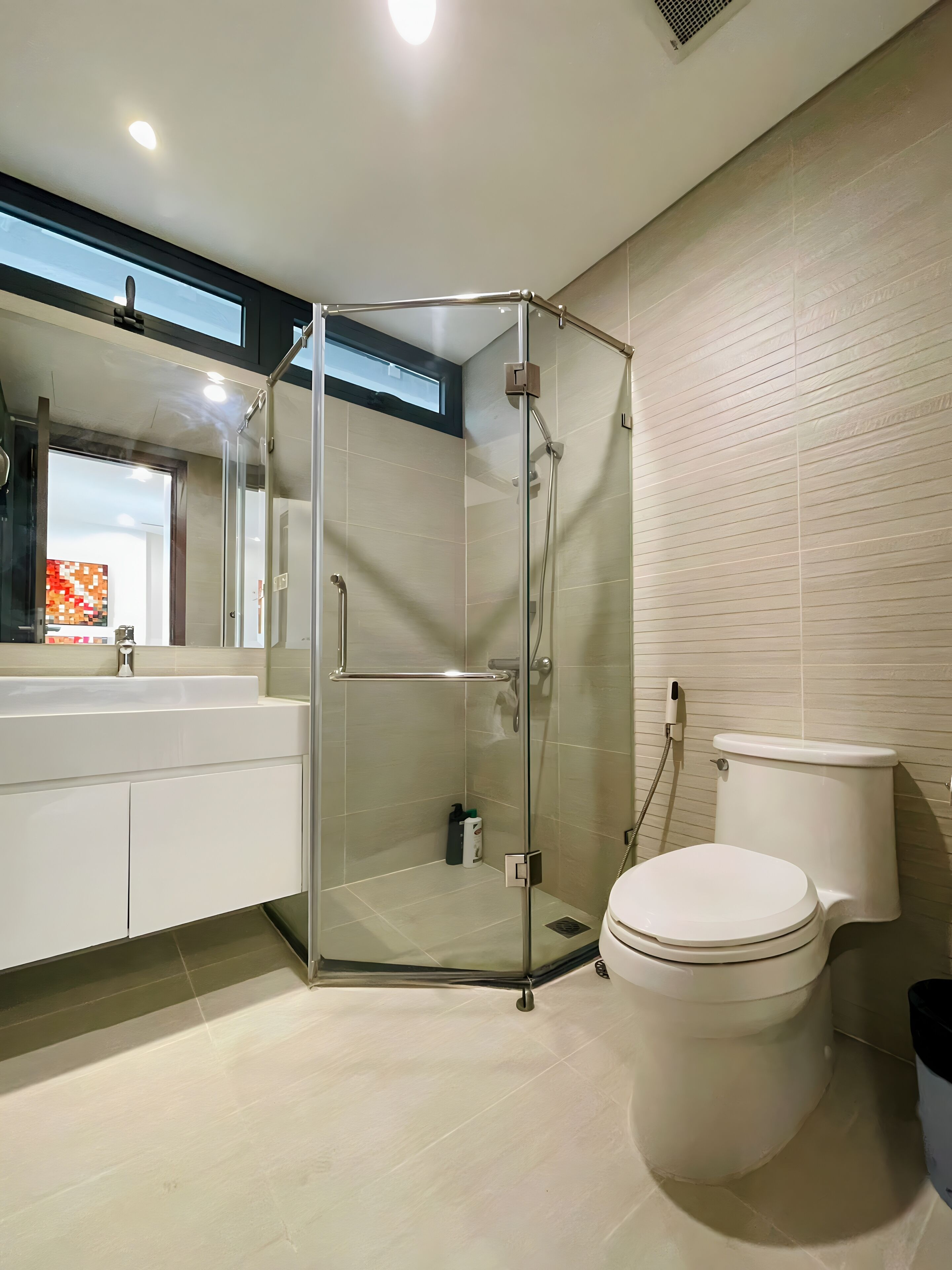 Een moderne badkamer met een douchecabine van glas, een wit toilet en een wastafel met spiegel.