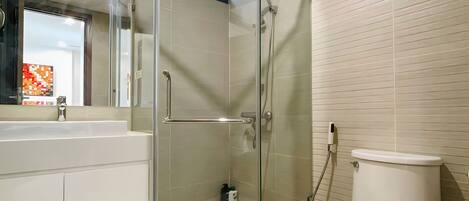 Een moderne badkamer met een douchecabine van glas, een wit toilet en een wastafel met spiegel.