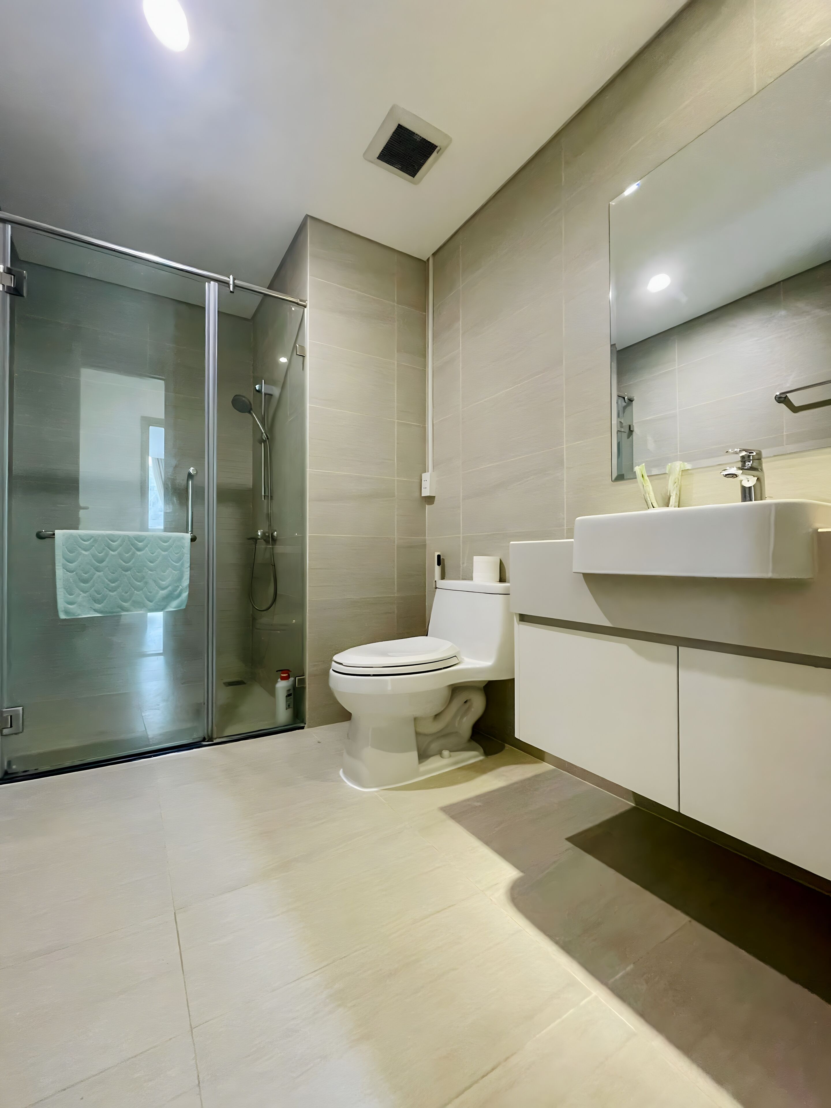 Een moderne badkamer met een douchecabine van glas, een toilet en een wastafel met spiegel.