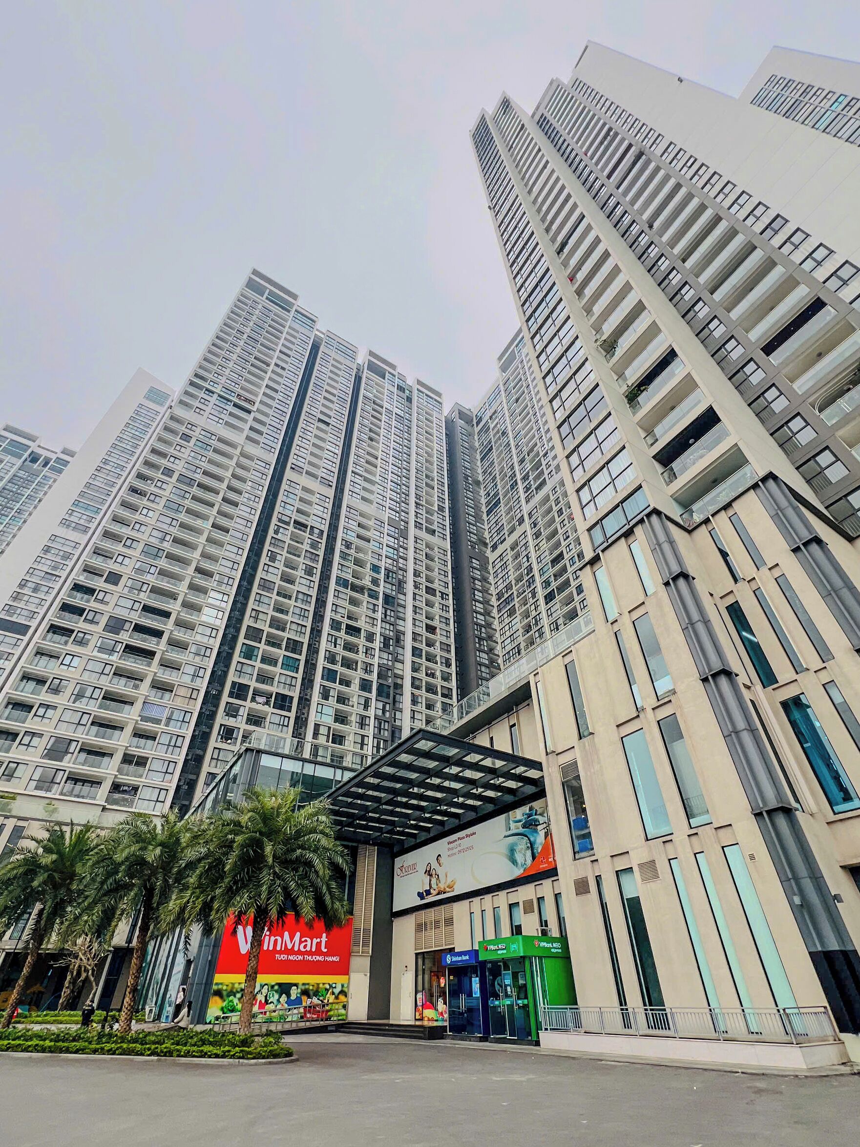 A high-rise building with multiple floors, a covered entrance, and a prominent VinMart sign.