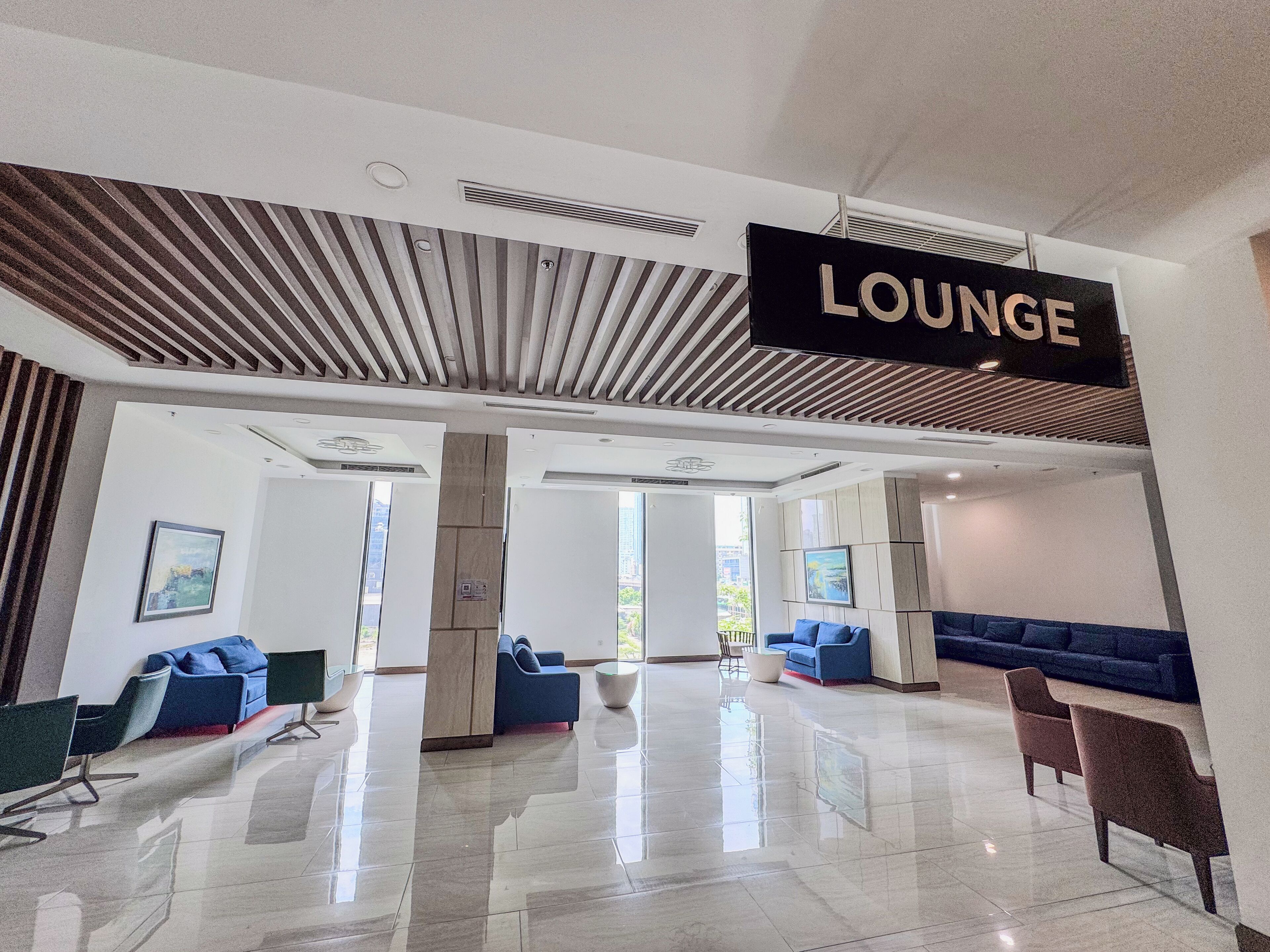 A modern lounge area with a polished floor, blue seating, and a 'LOUNGE' sign.
