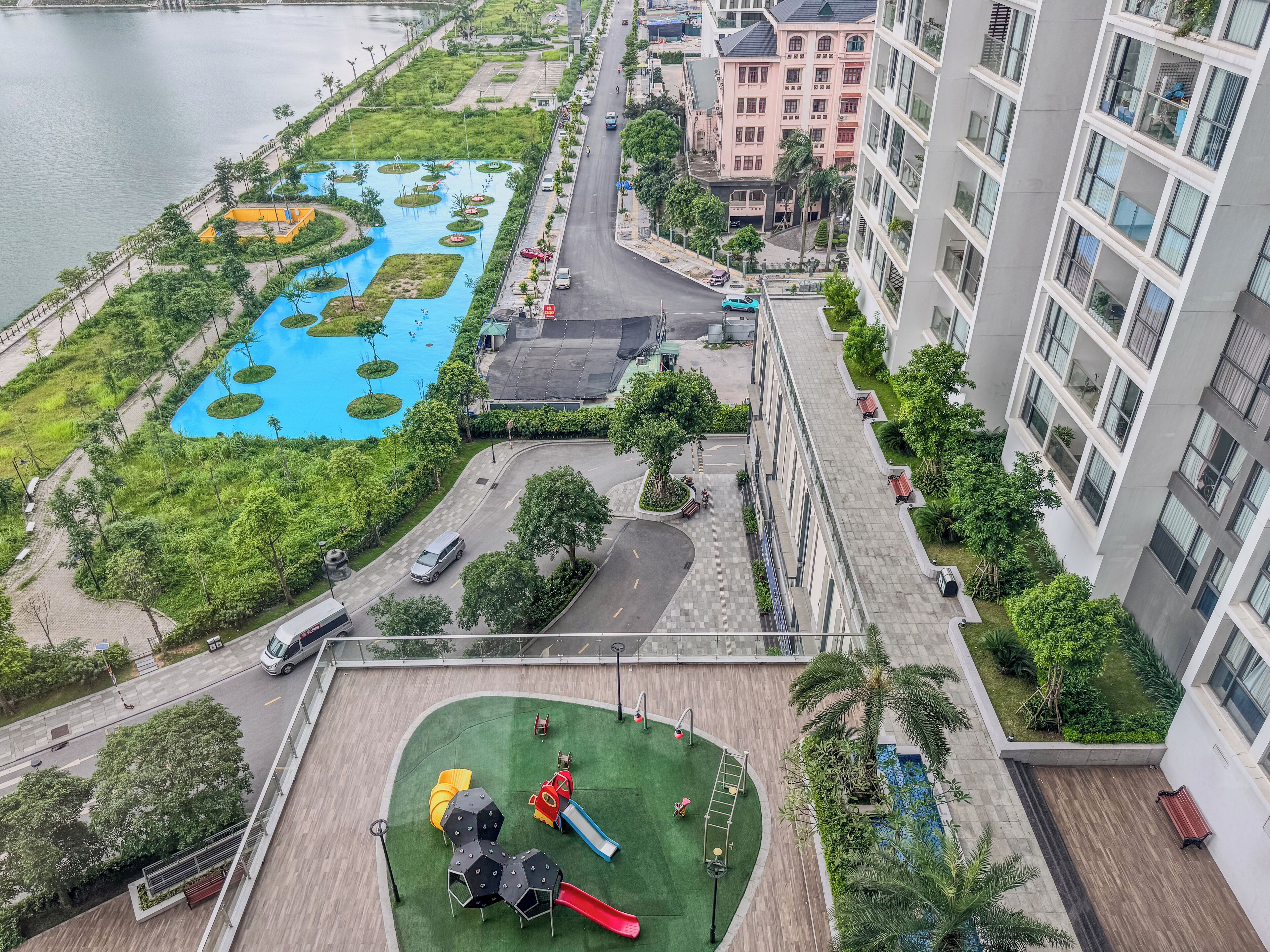 Zona residencial con piscina, parque infantil y una calle con vehículos.