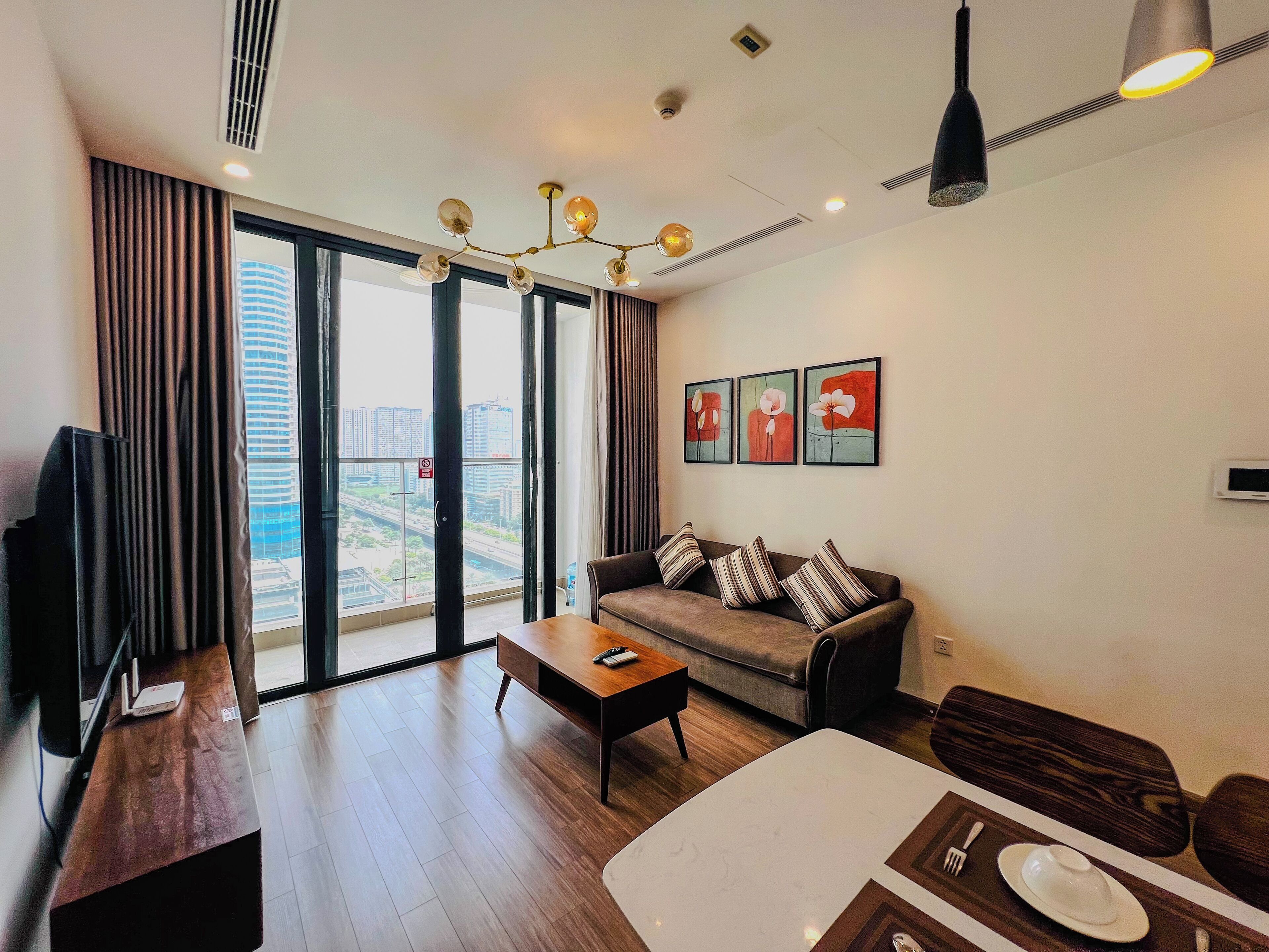 A modern living room with a sofa, a coffee table, and a dining area with a table set for two.