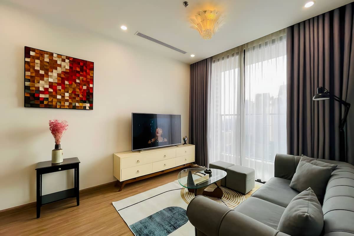 Un salon moderne avec un téléviseur à écran plat, un canapé, une table basse et un vase décoratif.