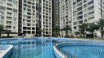 A modern high-rise building with a swimming pool featuring blue mosaic tiles.